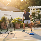 A person practicing pickleball shots solo against a training rebounder board in a sunlit backyard.